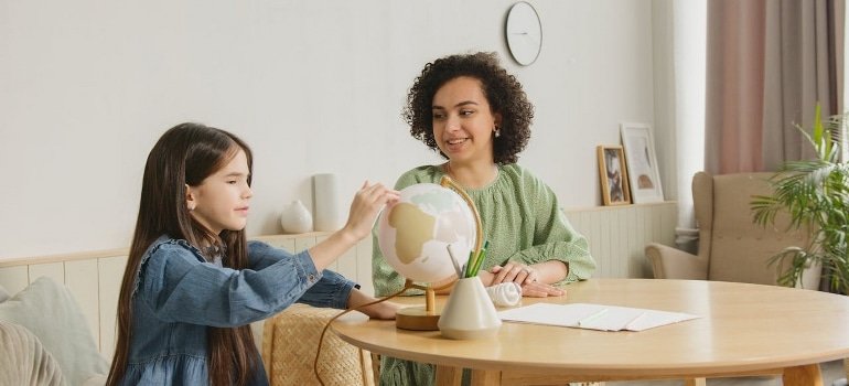 woman and girl looking at globe to handle international moving fears