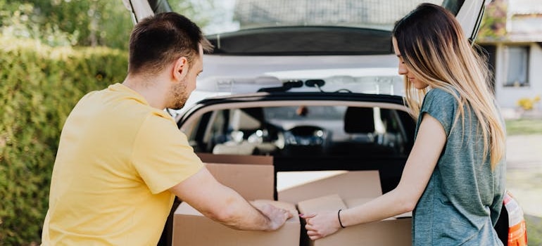 A couple putting carton boxes in a car