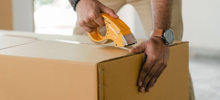 a man taping a box providing packing services for overseas shipping 