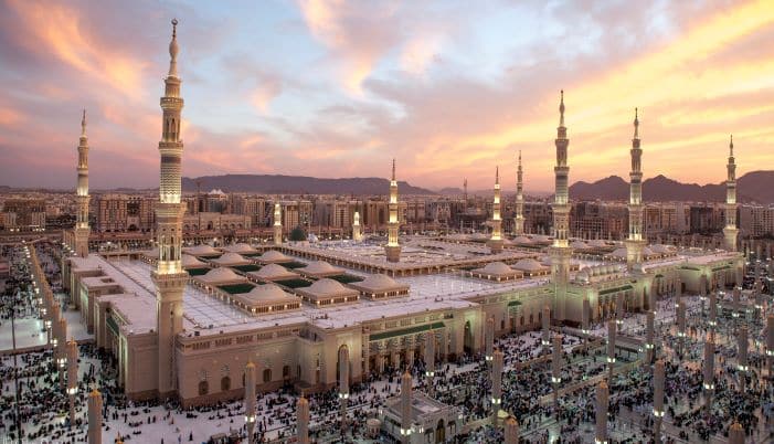 Night view of a grand mosque in Saudi Arabia, beautifully lit against the backdrop of the city, representing the country’s blend of cultural heritage and modernity, making it a unique destination for international relocation.