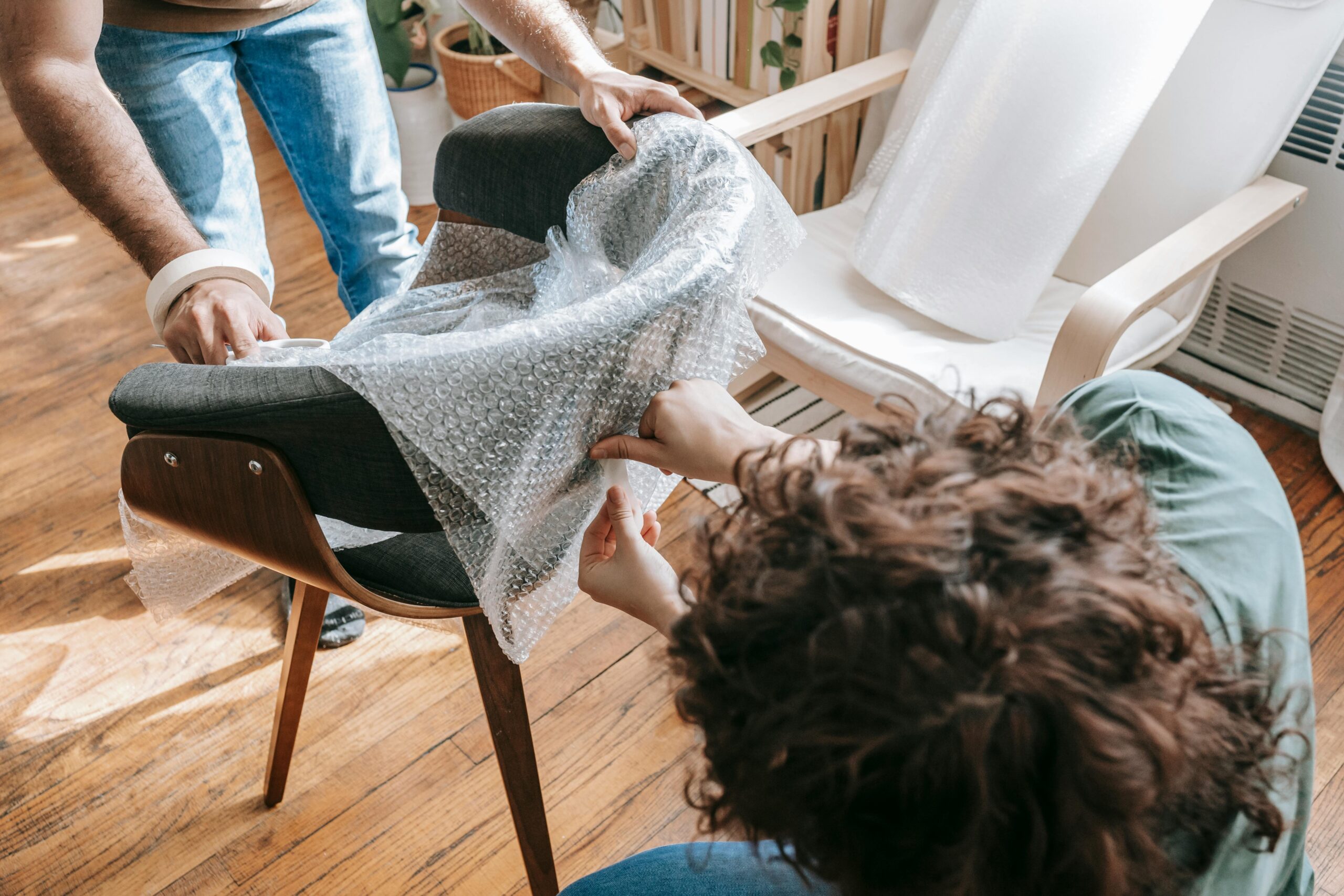 Couple Covering A Chair With Bubble Wrap
