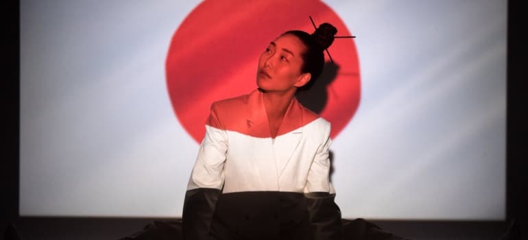 a japanese girl sitting in front of a japanese flag