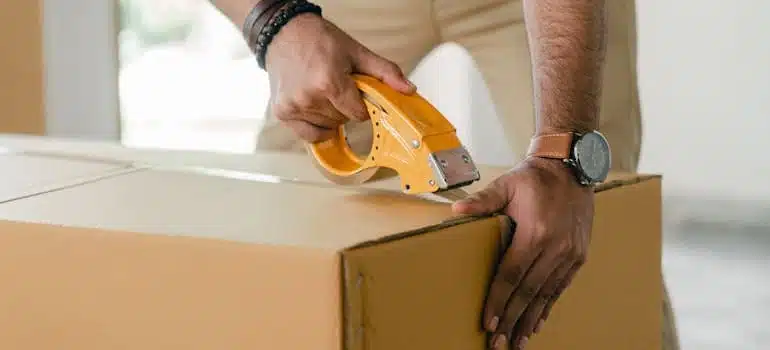 a person taping a box, packing supplies you’ll need for your international move