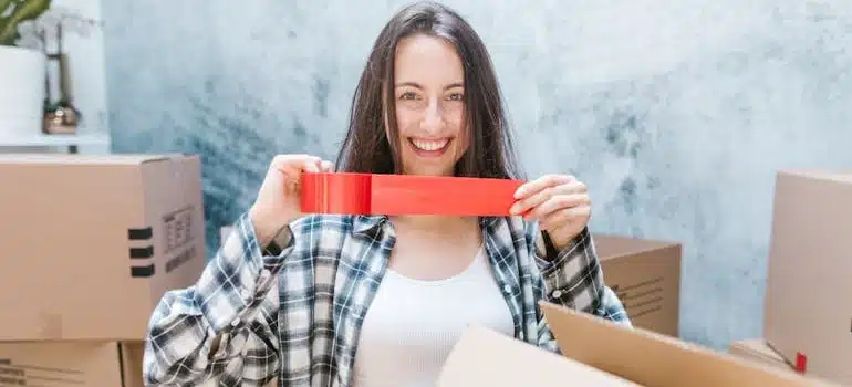 a person holding a tape, packing supplies you’ll need for your international move