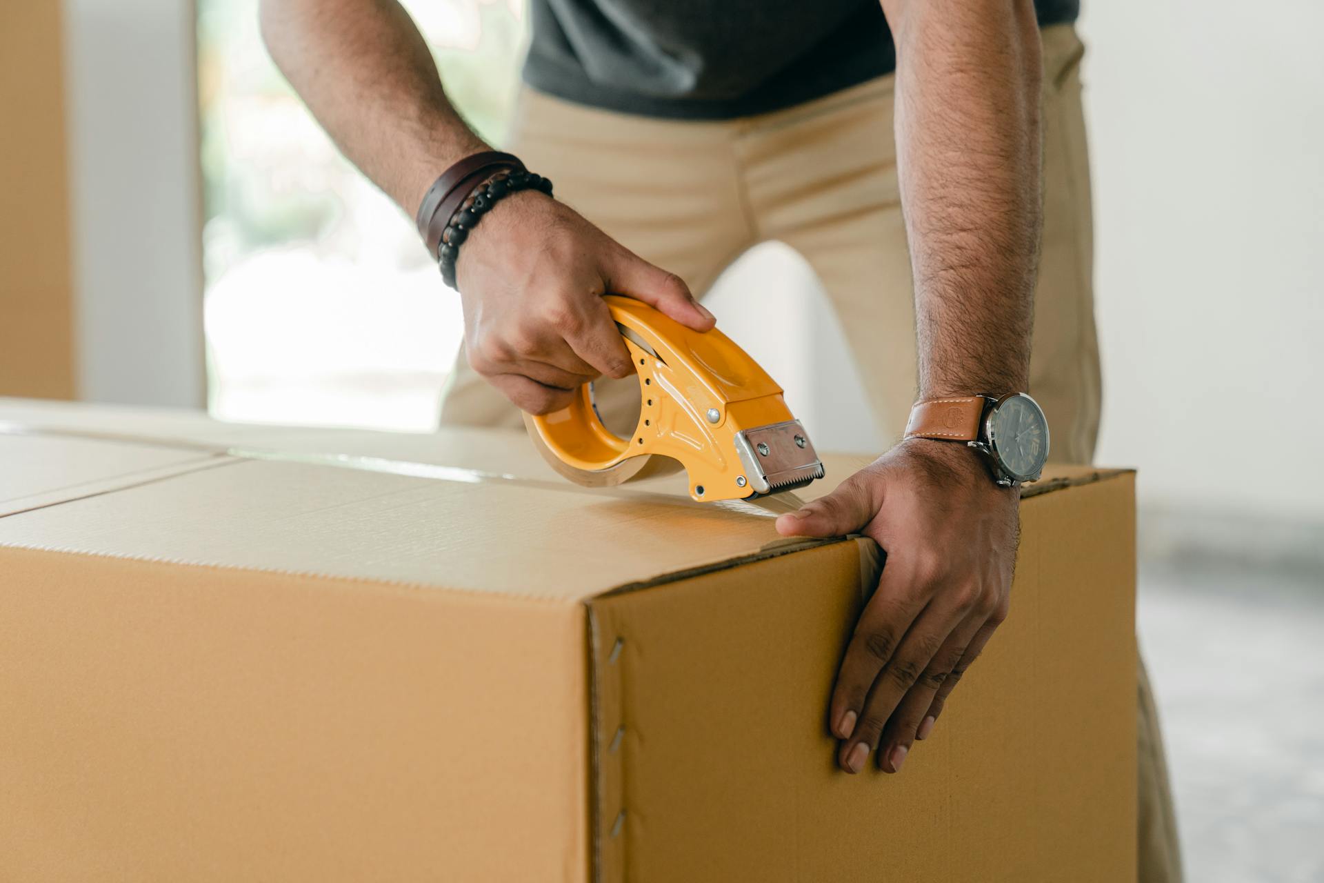 a person taping a box before Renting Storage in NJ During International Relocation