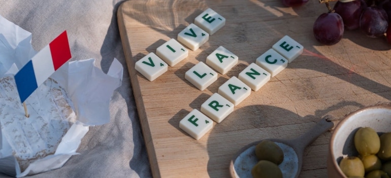 a wooden board, a small french flag and some food on the table cloth 