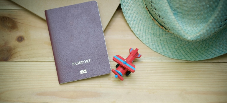 Travel essentials for downsizing for an international move, including a passport and hat.