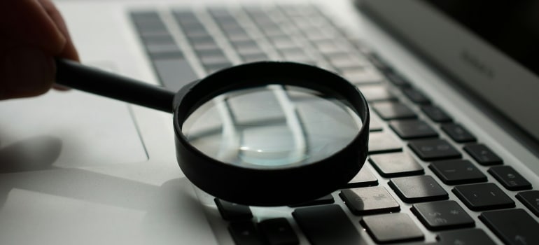 Person using a a magnifying glass to find U.S. banks that make it easy to manage finances from abroad