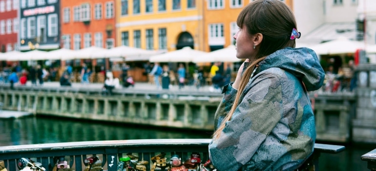 A woman in a stylish raincoat admiring the waterfront of Nyhavn, Copenhagen—a hub for creative minds in European Cities for Fashion Designers.