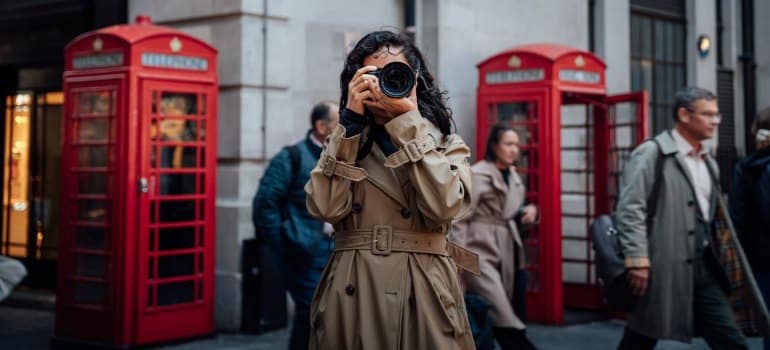 A photographer capturing the busy streets of London, framed by the city’s classic red telephone booths.