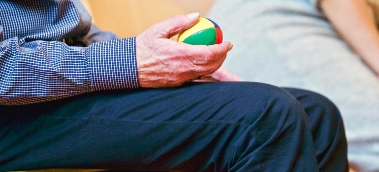 An older man with a ball in his hand relying on aussie health and wellness,