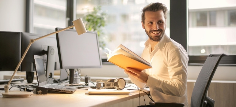 Photo of Man Holding a Book and  Embracing the Nordic Lifestyle