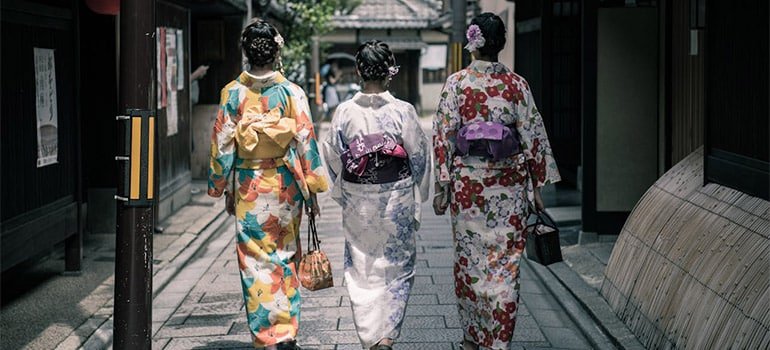 Three Geisha Walking Between Buildings